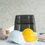 Foto: To hjelmer på en pult sammen med kaffe, PC og dokumenter