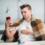 Syk mann med pledd over skuldrene sender SMS