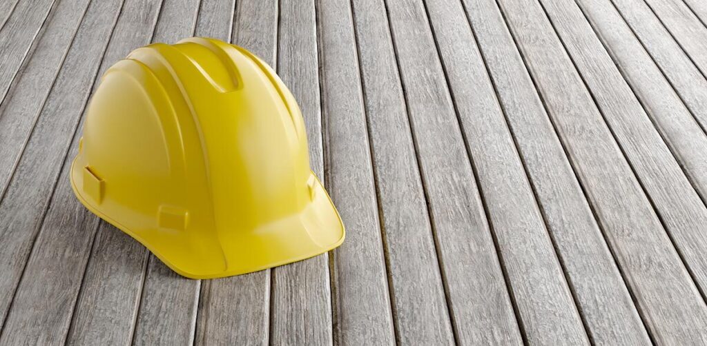 Gul arbeidshjelm på tregulv.