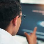 Mann sett bakfra med en pc-skjerm foran seg