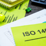 Papirer på et bord med en gul lapp med teksten ISO 14001